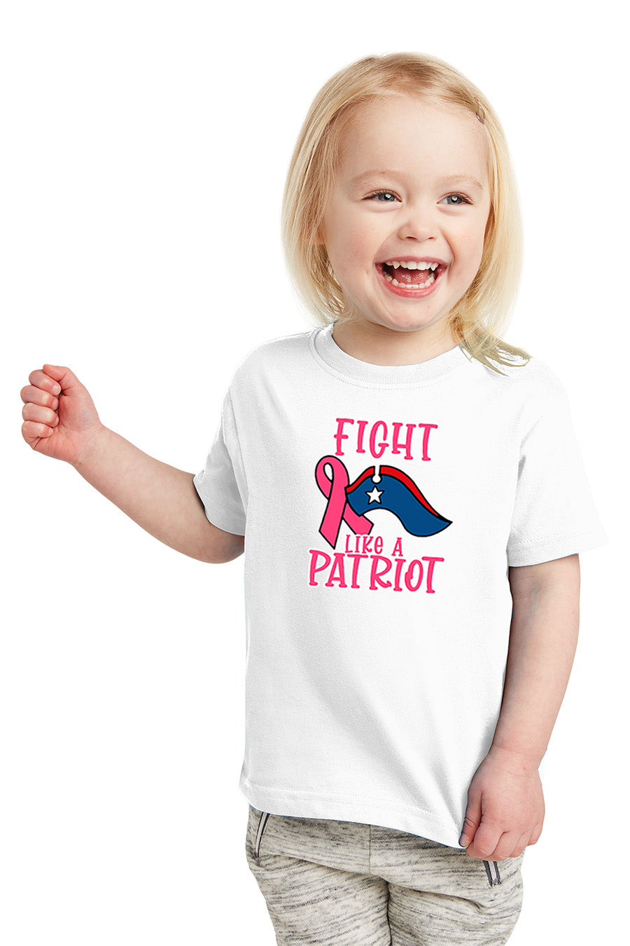 Child wearing a white t-shirt with a pink ribbon and American flag design, smiling on a white background. Paper Street Print Co, Blairstown, NJ.