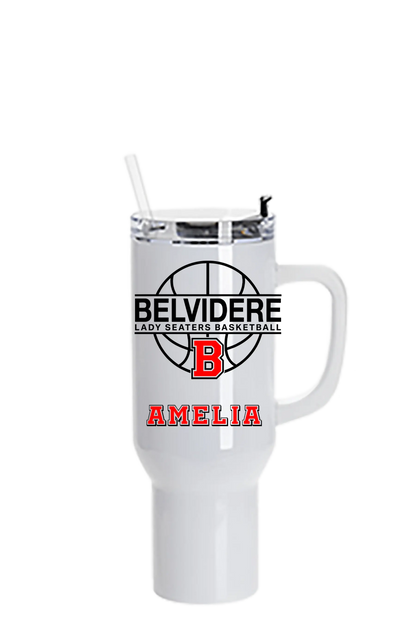 A white insulated travel tumbler with a handle, clear lid, and straw. The front features a black basketball graphic with the text 'BELVIDERE LADY SEATERS BASKETBALL', a red block 'B', and the name 'AMELIA' in red. Paper Street Print Co, Blairstown, NJ.