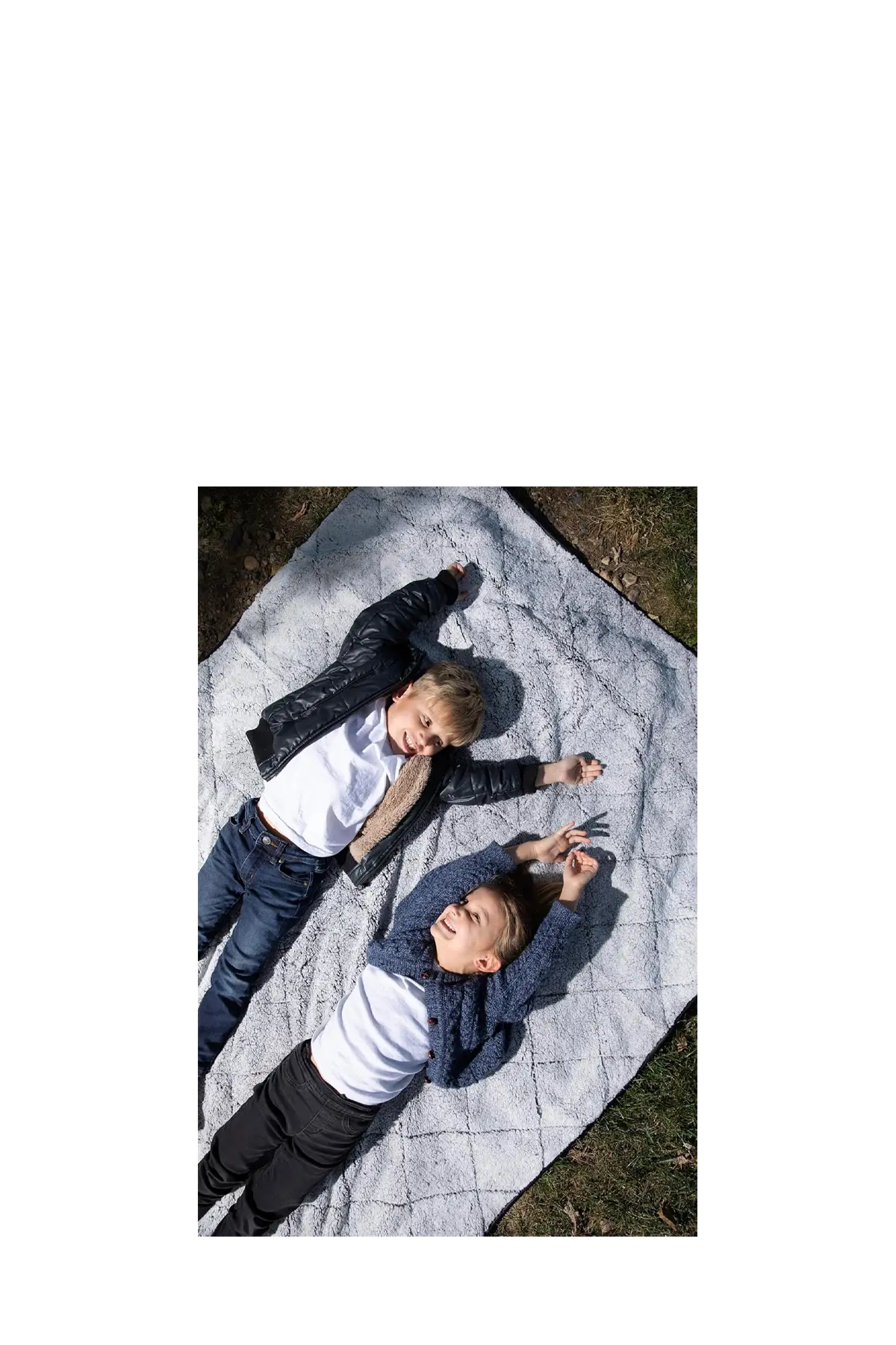Two children lying on a very comfortable waterproof blanket outdoors. CSA Cheshire Soccer Academy, Paper Street Print Co, Blairstown, NJ.