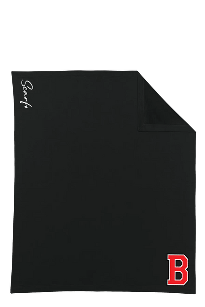 A black square towel or blanket with a folded top-right corner, featuring a white script logo on the left side and a red block letter 'B' on the bottom right, shown on a plain white background. Belvidere Lady Seaters Basketball, Paper Street Print Co, Blairstown, NJ.