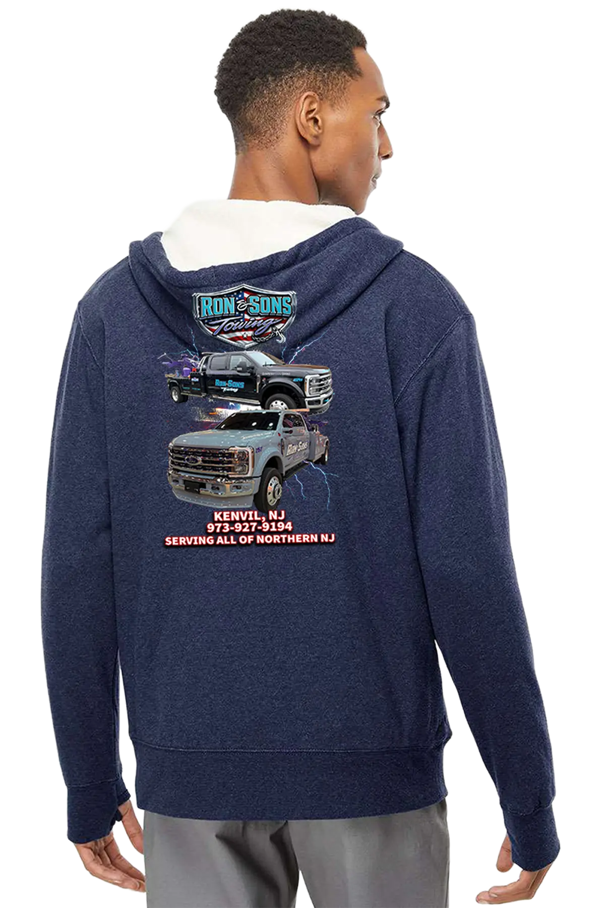 Person wearing a navy hoodie with a truck graphic and text on the back, on a white background. Ron and Sons Towing, Paper Street Print Co, Blairstown, NJ.