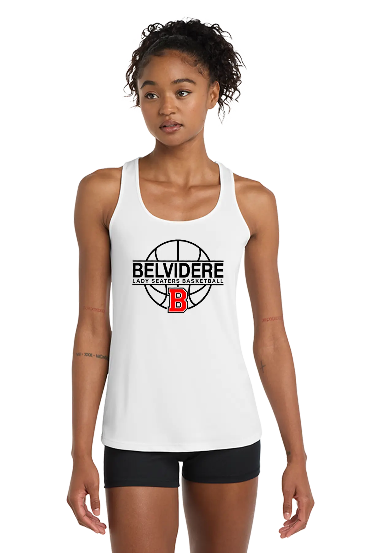 A woman modeling a white racerback tank top with a black and red Belvidere Lady Seaters Basketball logo on the chest, paired with black athletic shorts, against a plain white background. Paper Street Print Co, Blairstown, NJ.
