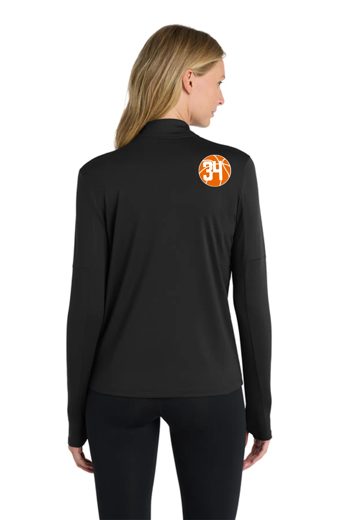 A woman shown from the back wearing a black long-sleeve athletic top with an orange circular '34' logo on the upper back, paired with black leggings, against a plain white background. Belvidere Lady Seaters Basketball, Paper Street Print Co, Blairstown, NJ.