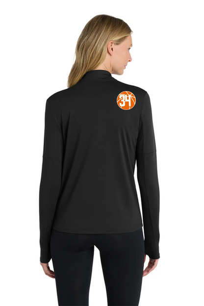 A woman shown from the back wearing a black long-sleeve athletic top with an orange circular '34' logo on the upper back, paired with black leggings, against a plain white background. Belvidere Lady Seaters Basketball, Paper Street Print Co, Blairstown, NJ.