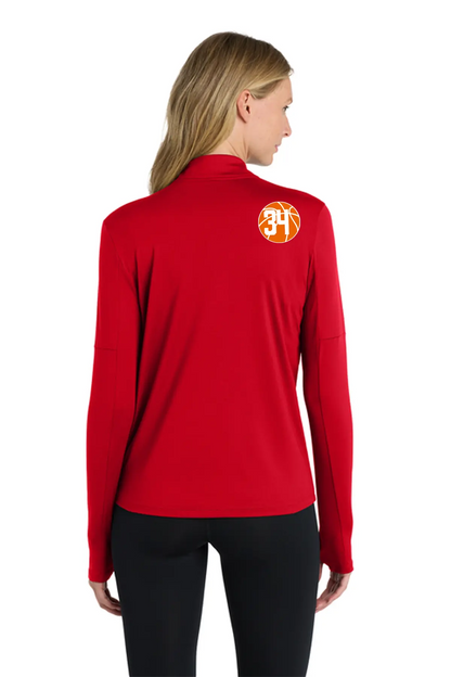A woman shown from the back wearing a bright red long-sleeve athletic top with a circular orange and yellow '34' logo on the upper back, paired with black leggings, against a plain white background. Belvidere Lady Seaters Basketball, Paper Street Print Co, Blairstown, NJ.