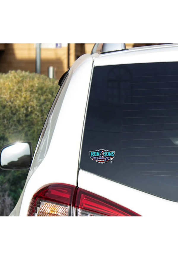 Car window with a Ron and Sons Towing decal on a white car against a blurred outdoor background. Paper Street Print Co, Blairstown, NJ.