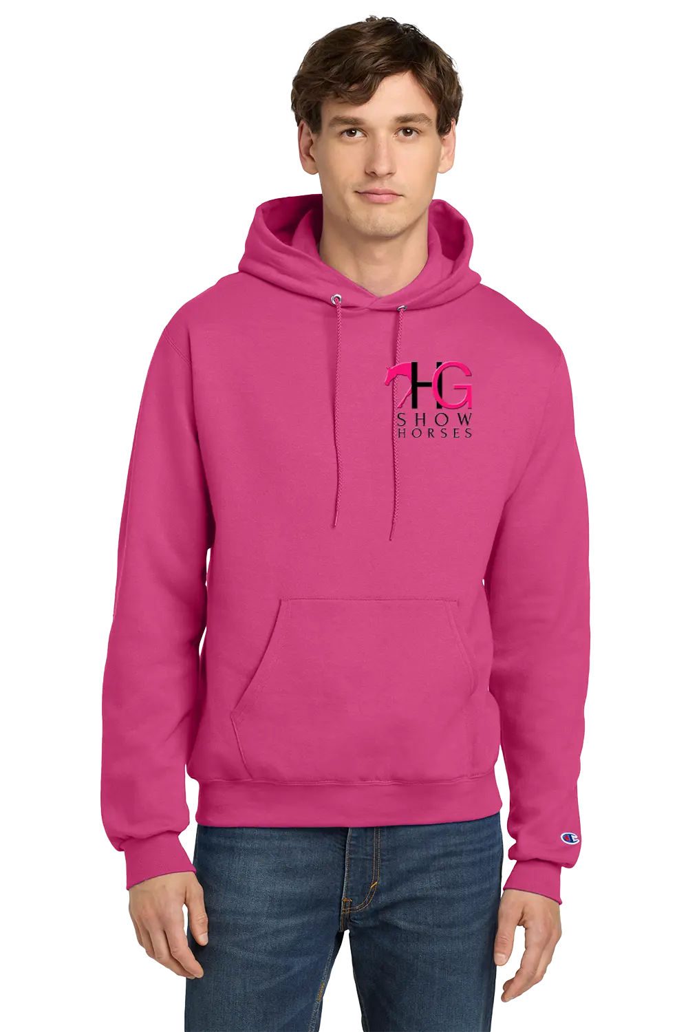 A man wearing a bright pink pullover hoodie with a 'HG SHOW HORSES' logo on the left chest and a small Champion logo on the right sleeve cuff, paired with blue jeans, against a plain white background. HG Show Horses, Paper Street Print Co, Blairstown, NJ.