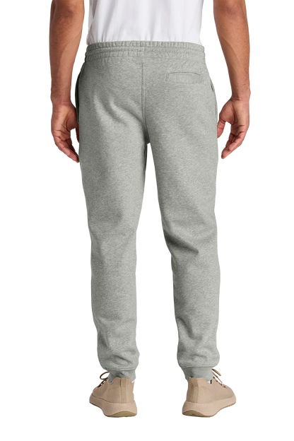 A person shown from the back wearing light heather gray sweatpants, a white shirt, and beige sneakers against a plain white studio background. HG Show Horses, Paper Street Print Co, Blairstown, NJ.